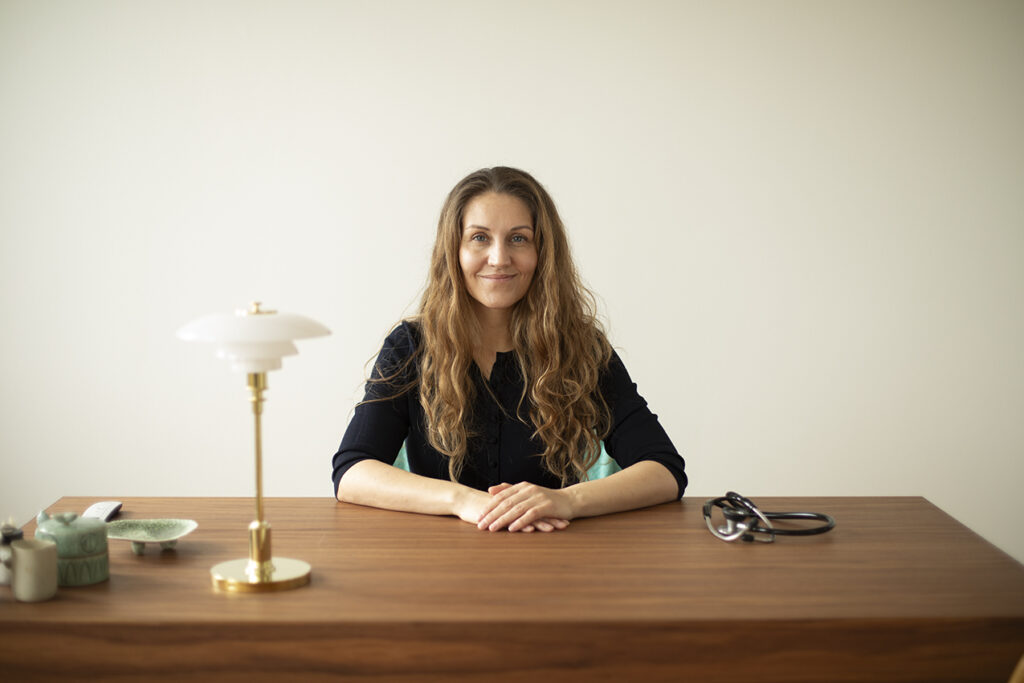 Pia Cajsa, ekspert i brystløft med lollipop-teknik, gennemgår operationsplanen i klinikkens lyse kontor, der er præget af nordisk minimalisme og dansk design (PH lampe)